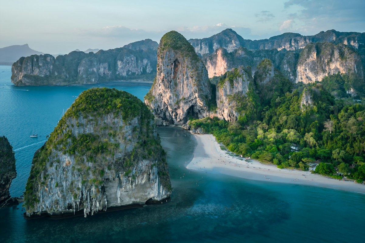 Limestone karsts rise from the ocean near a tropical beach