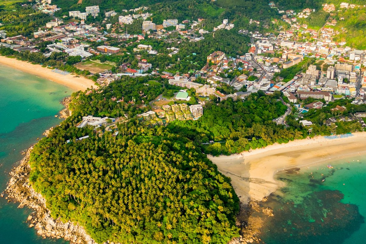 Aerial view of a tropical coastal town with lush green hills