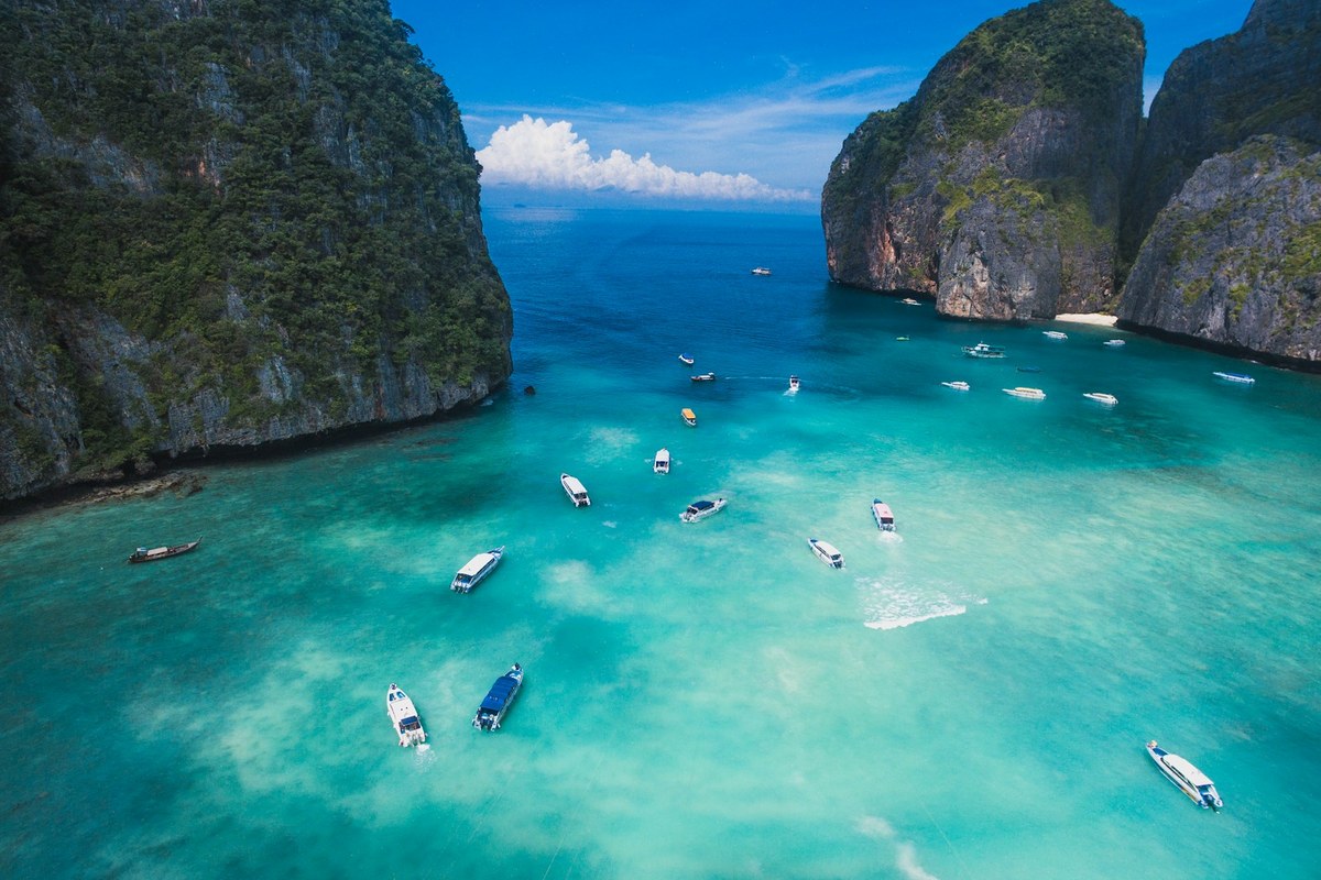 Boats on the turquoise water of Maya Bay between limestone cliffs in Thailand